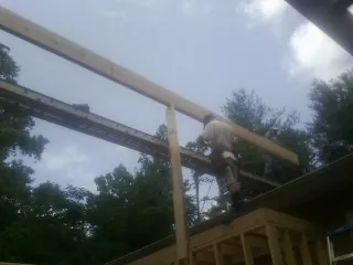 Carpenter setting a ridge beam over a new addition frame — Ice Dam Removal by Roofing Brothers in Mcpherson