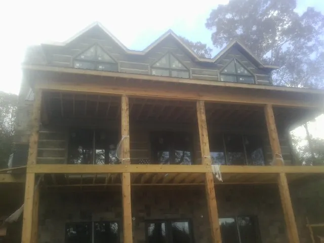 Dormers and porch framing on a large log home under construction — Roof Coating work by our crew in Mcpherson