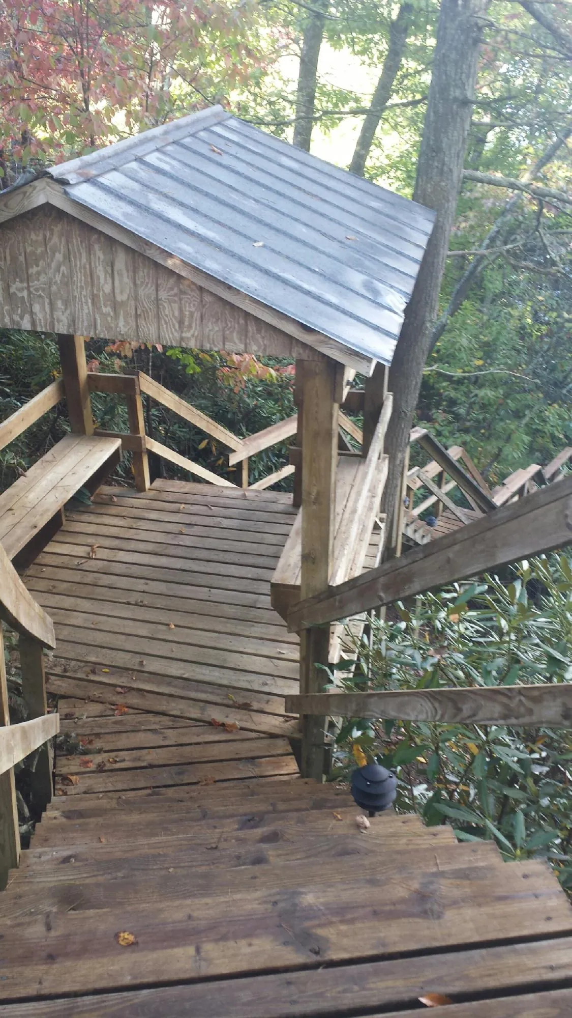 Metal roofed shelter over wooden steps on a wooded walkway — Skylight Repair & Installation work by our crew in Mcpherson