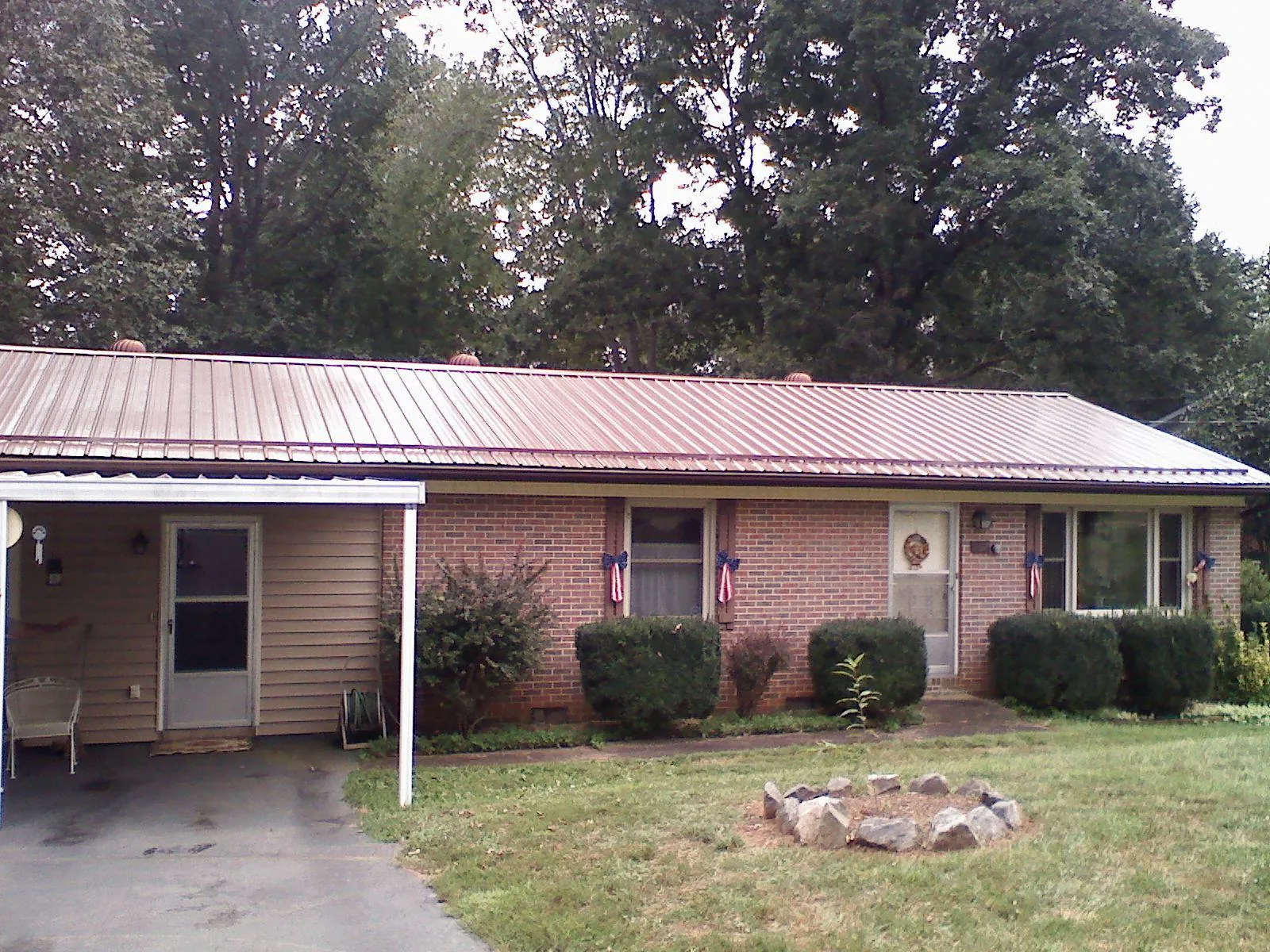 Bronze metal roof and carport on a brick ranch home — Roof Repair work by our crew in Mcpherson